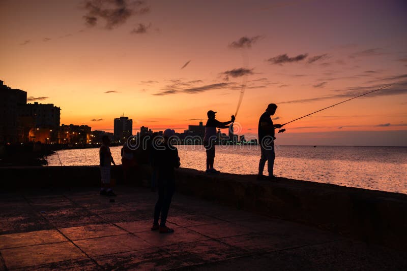 Silhueta dos pescadores e a skyline da cidade em Havana fotografia de stock Silhueta dos pescadores e a skyline da cidade em Havana fotografia de stock