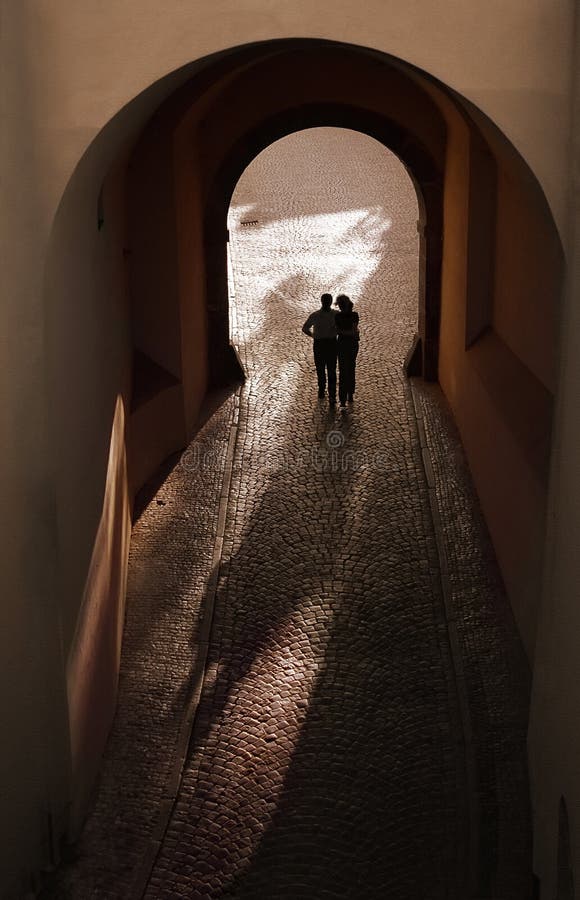 Romantic persons silhouette in arc, man and woman together at old stone street. Sepia colors. Prague. Romantic persons silhouette in arc, man and woman together at old stone street. Sepia colors. Prague