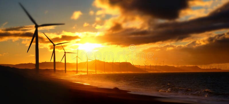 Silhuetas de geradores eólicos na costa oceânica foto de stock