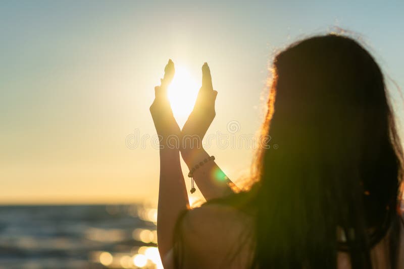 Silhuett av unga kvinnor händer som lättar på glad meditation och solnedgång mot gyllene timmes himmel på stranden royaltyfri bild