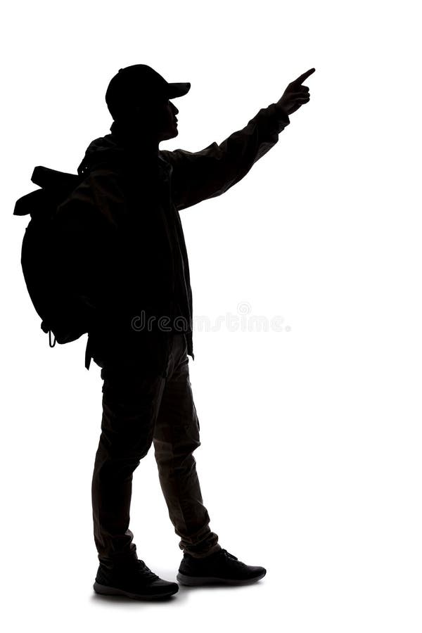 Silhouette of a man wearing a backpack looking like a traveler or hiker trekking.  He is pointing at something. Silhouette of a man wearing a backpack looking like a traveler or hiker trekking.  He is pointing at something