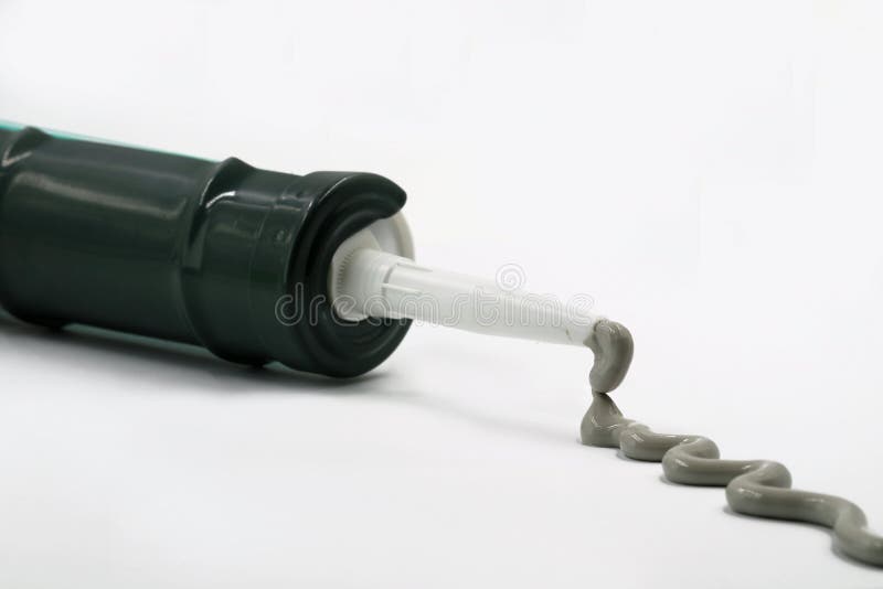 Silicone grigio dalla pistola del silicone isolata su bianco immagini stock Silicone grigio dalla pistola del silicone isolata su bianco immagini stock