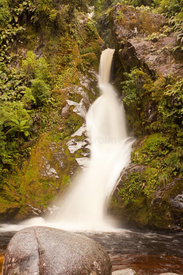 Silky forest waterfall cascading down rocky slope stock images
