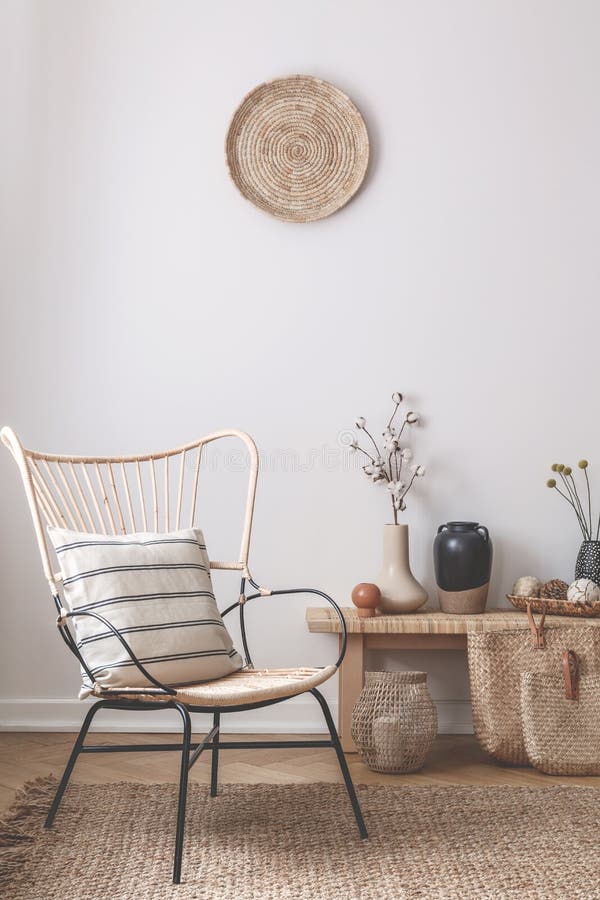 Wicker chair with striped pillow on it next to wooden table full of accessories such as vase, flowers and candles concept. Wicker chair with striped pillow on it next to wooden table full of accessories such as vase, flowers and candles concept