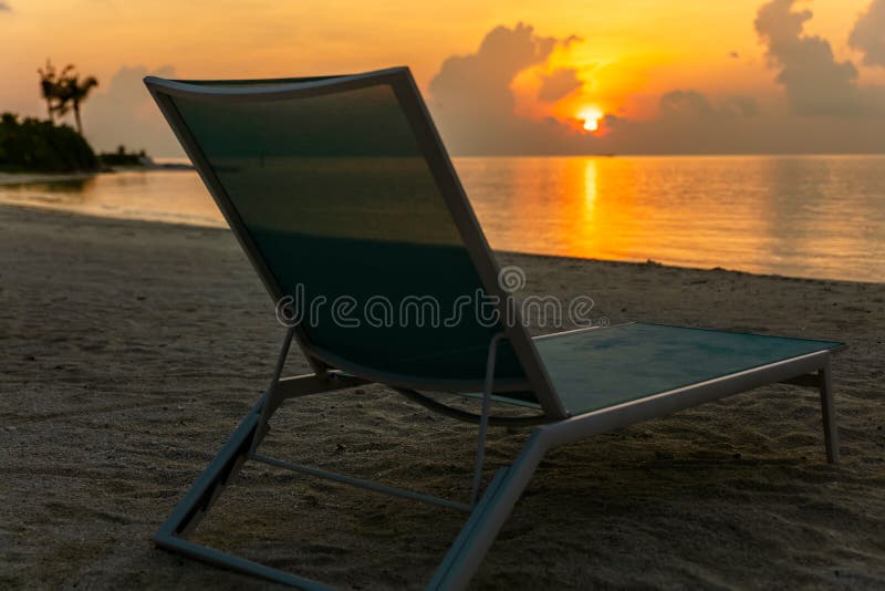 Silla de playa cómoda en el zapato solo del mar por tiempo de la puesta del sol foto de archivo libre de regalías Silla de playa cómoda en el zapato solo del mar por tiempo de la puesta del sol foto de archivo libre de regalías