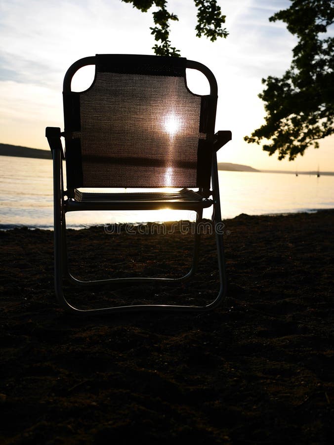 Silla plegable que se coloca en la orilla del lago foto de archivo libre de regalías Silla plegable que se coloca en la orilla del lago foto de archivo libre de regalías