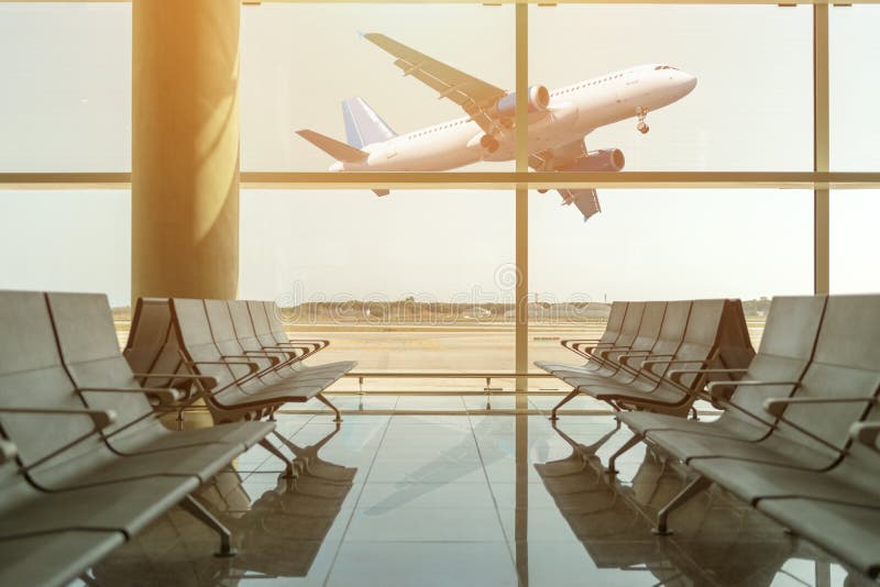 Sillas vacías en el pasillo de la salida en el aeropuerto en el fondo del aeroplano que saca en la puesta del sol concepto del re imagen de archivo Sillas vacías en el pasillo de la salida en el aeropuerto en el fondo del aeroplano que saca en la puesta del sol concepto del re imagen de archivo