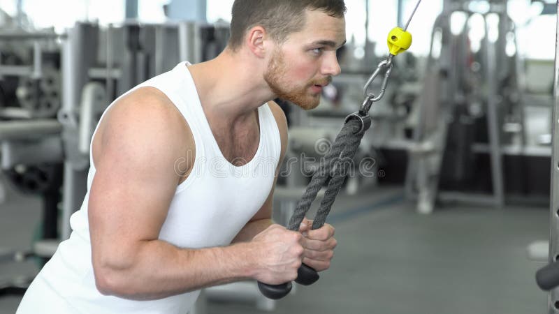 Silny sportowy mężczyzna w koszulce przy gym szkoleniem na blokowym przyrządzie CrossFit szkolenie zdjęcia stock Silny sportowy mężczyzna w koszulce przy gym szkoleniem na blokowym przyrządzie CrossFit szkolenie zdjęcia stock