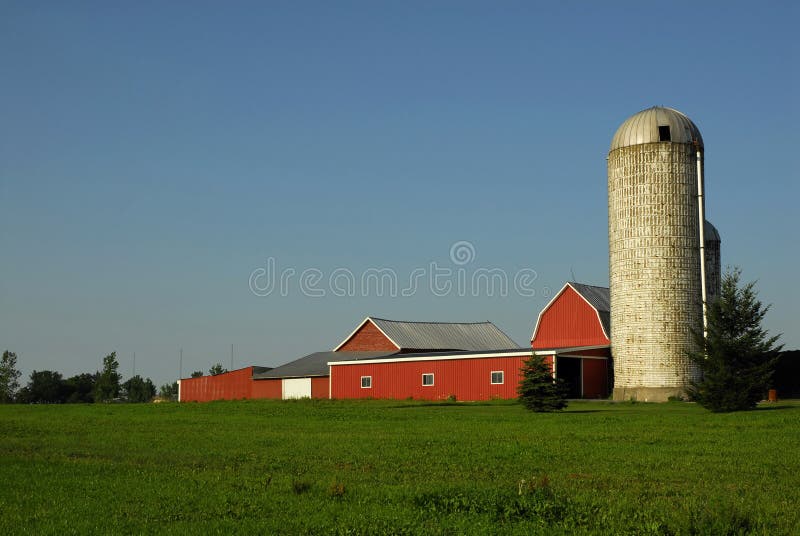 Silos under a cloudy sky with foreground greenery