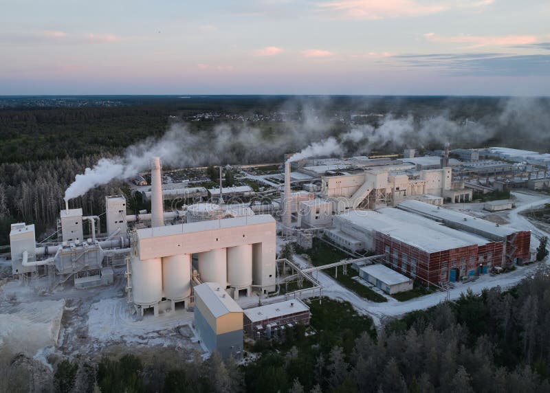 Round silos for calx storage at modern silica bricks manufacturing plant at sunset bird eye view. Large production factory in wood. Round silos for calx storage at modern silica bricks manufacturing plant at sunset bird eye view. Large production factory in wood