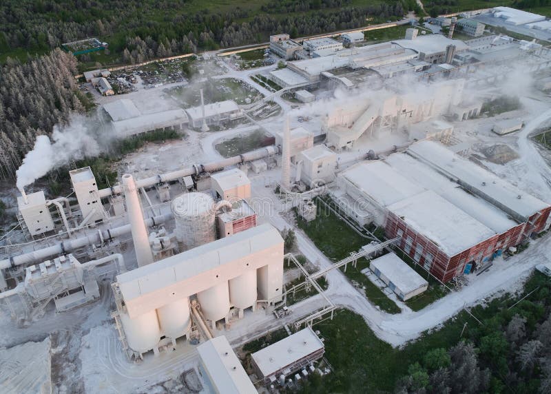 Round silos for calx storage at modern silica bricks manufacturing plant at sunset bird eye view. Large production factory in wood. Round silos for calx storage at modern silica bricks manufacturing plant at sunset bird eye view. Large production factory in wood