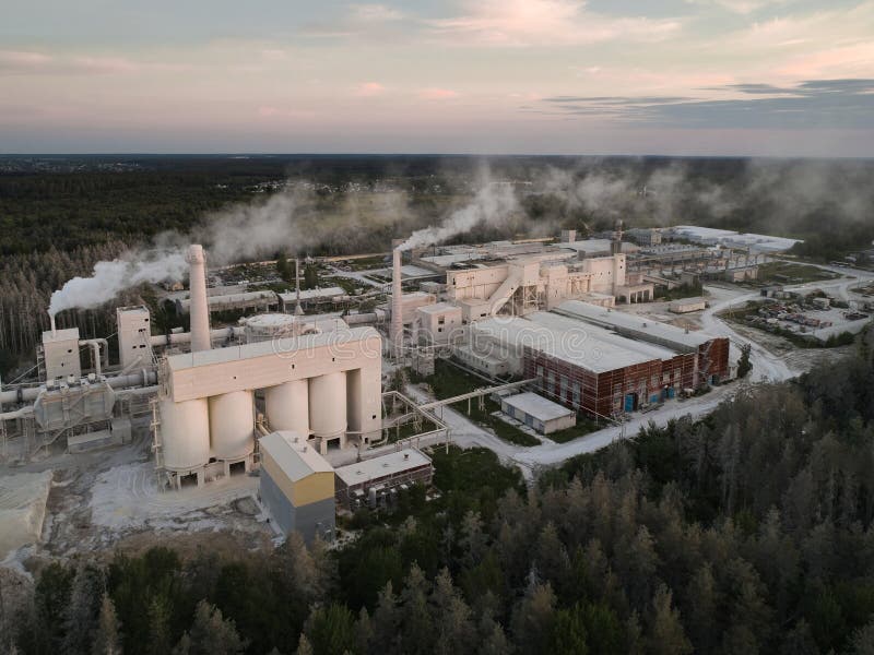 Round silos for calx storage at modern silica bricks manufacturing plant at sunset bird eye view. Large production factory in wood. Round silos for calx storage at modern silica bricks manufacturing plant at sunset bird eye view. Large production factory in wood