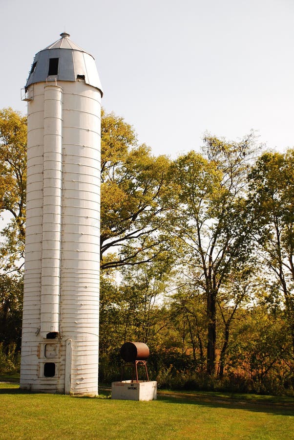 This is a shot of a white silo next to a tree line. This is a shot of a white silo next to a tree line.