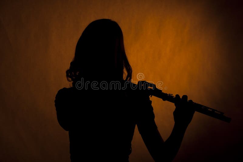 Silueta adolescente de la muchacha del jugador de flauta en amarillo imagenes de archivo Silueta adolescente de la muchacha del jugador de flauta en amarillo imagenes de archivo