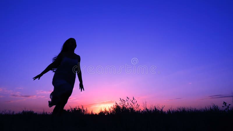 Silueta de la chica joven que corre contra el cielo rosado