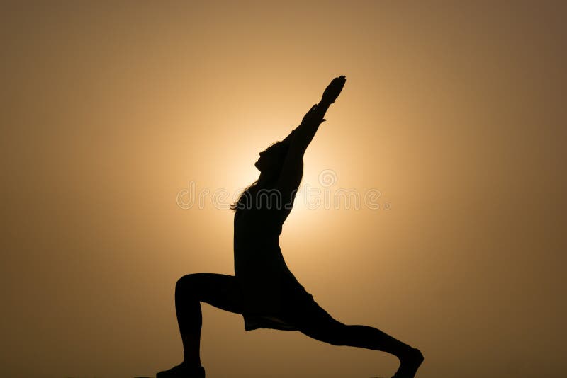Silueta de la mujer que realiza yoga en la puesta del sol foto de archivo Silueta de la mujer que realiza yoga en la puesta del sol foto de archivo