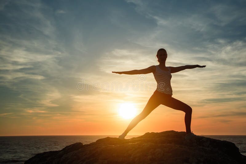 Silueta de la mujer de la yoga que hace ejercicios de la aptitud en la playa del océano imágenes de archivo libres de regalías Silueta de la mujer de la yoga que hace ejercicios de la aptitud en la playa del océano imágenes de archivo libres de regalías