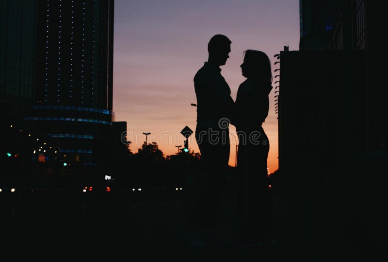 Silueta de pares felices jovenes en el amor que se besa en la calle de la ciudad en la puesta del sol fotografía de archivo libre de regalías Silueta de pares felices jovenes en el amor que se besa en la calle de la ciudad en la puesta del sol fotografía de archivo libre de regalías