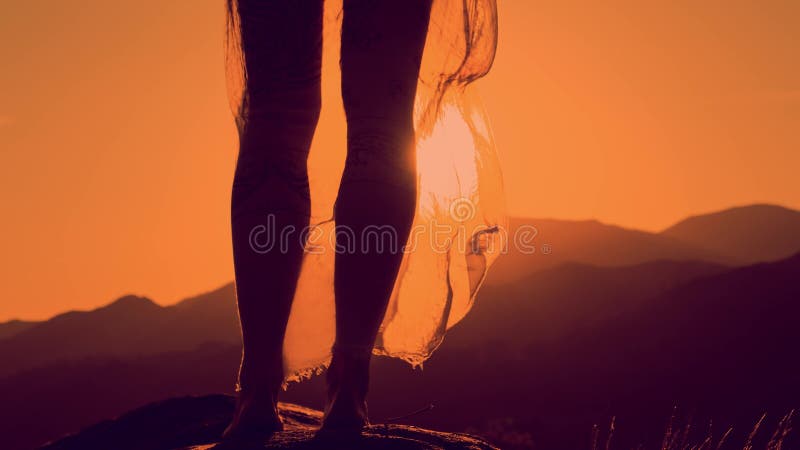 Silueta de piernas femeninas, fondo de montaña de puesta de sol