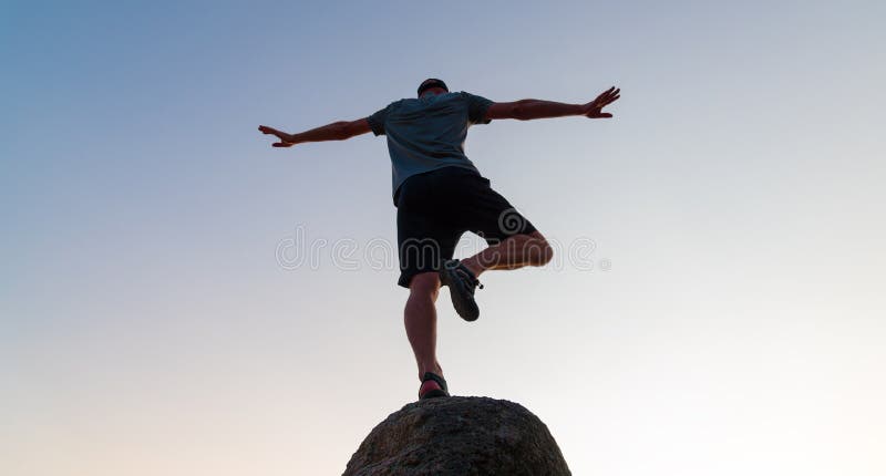 Silueta de un hombre practicando yoga en una roca exterior al atardecer concepto de equilibrio y calmar la mente y el cuerpo imagen de archivo
