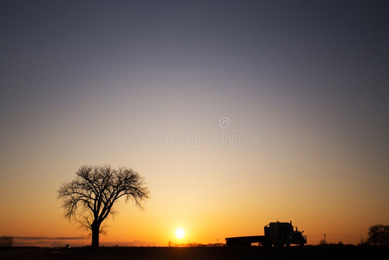 Silueta de un árbol y semi camión en la puesta del sol fotos de archivo Silueta de un árbol y semi camión en la puesta del sol fotos de archivo