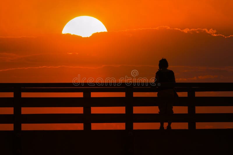 Silueta de una mujer en un puente en la puesta del sol imagen de archivo libre de regalías Silueta de una mujer en un puente en la puesta del sol imagen de archivo libre de regalías