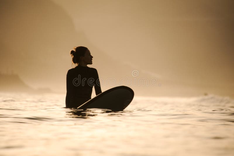 Silueta de una surfista en las aguas imágenes de archivo libres de regalías Silueta de una surfista en las aguas imágenes de archivo libres de regalías