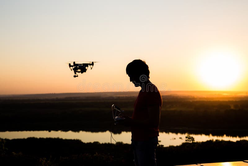 Silueta del abejón, quadrocopter con el vuelo de la cámara de la foto en el cielo foto de archivo libre de regalías Silueta del abejón, quadrocopter con el vuelo de la cámara de la foto en el cielo foto de archivo libre de regalías