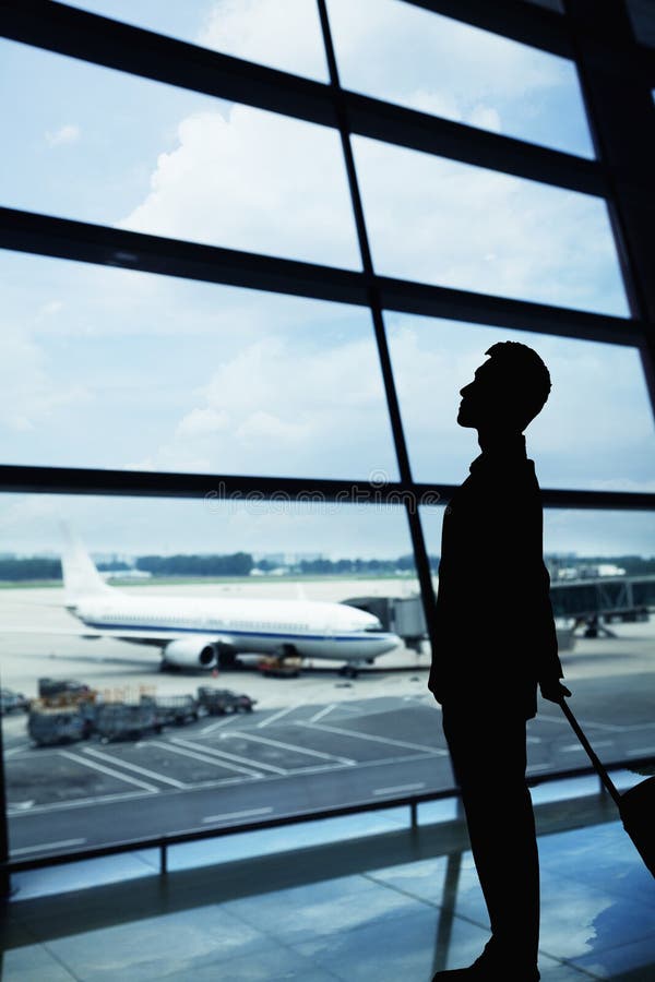 Silueta del hombre de negocios que espera en el aeropuerto y que mira hacia fuera la ventana foto de archivo libre de regalías Silueta del hombre de negocios que espera en el aeropuerto y que mira hacia fuera la ventana foto de archivo libre de regalías