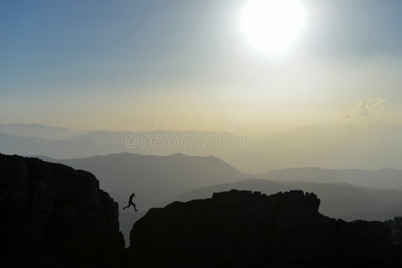 Silueta del hombre que salta en las rocas imagen de archivo Silueta del hombre que salta en las rocas imagen de archivo