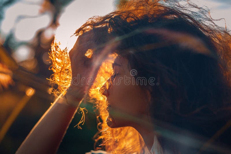Silueta hermosa de la mujer joven en un campo en la puesta del sol imagen de archivo libre de regalías