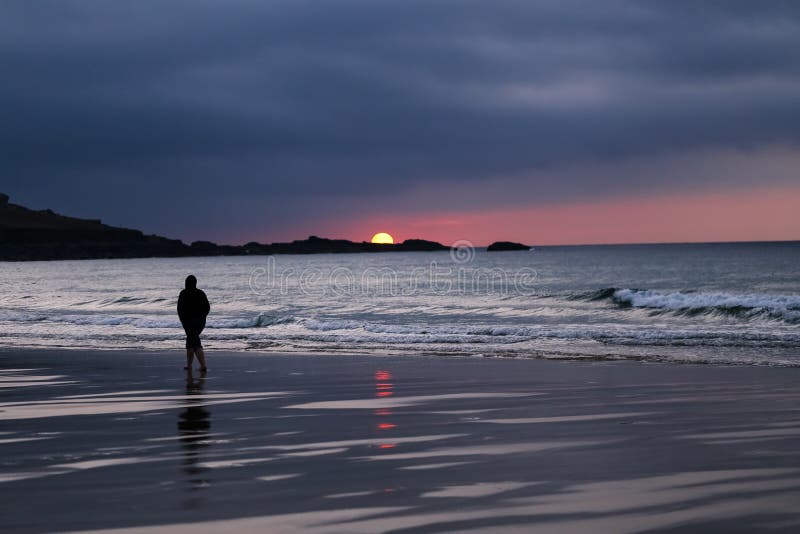 Silueta negra y blanca del hombre que camina solamente en la playa durante el Su imagen de archivo Silueta negra y blanca del hombre que camina solamente en la playa durante el Su imagen de archivo