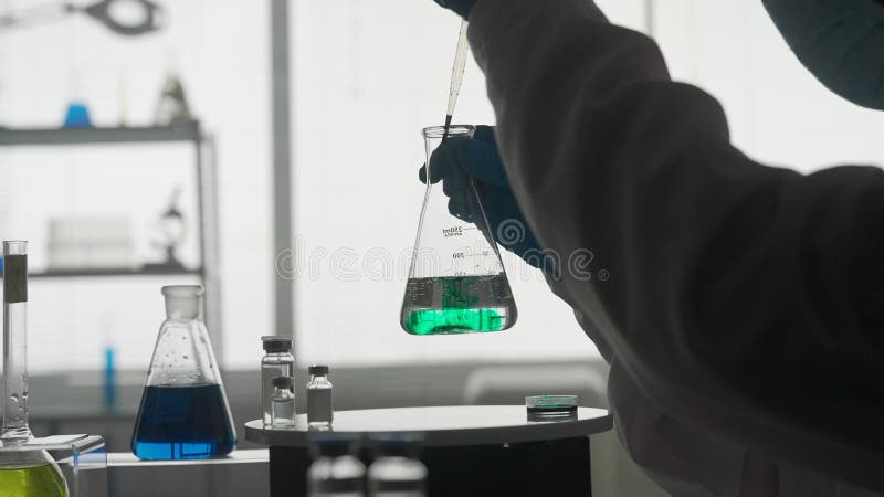Silueta oscura de un científico masculino que realiza un experimento científico. un hombre que utilice una pipeta añadirá un react almacen de metraje de vídeo