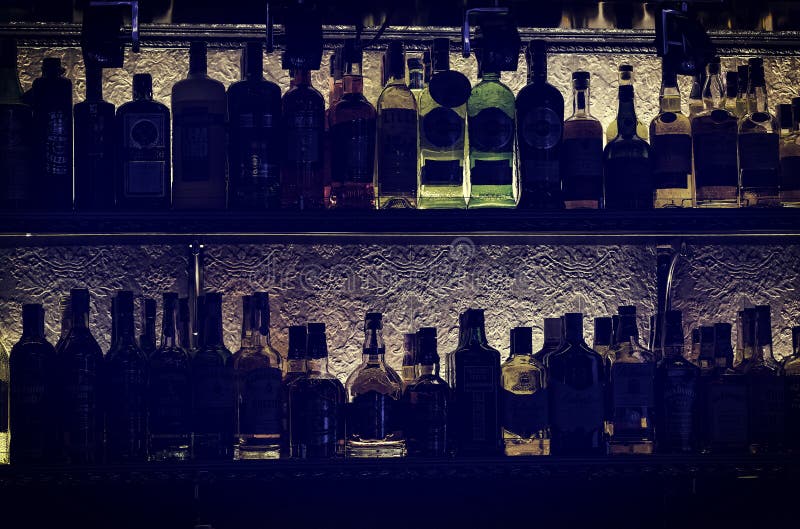 Siluetas de botellas con los templos del alcohol de la culpabilidad en un estante en una barra del club nocturno imagen de archivo libre de regalías Siluetas de botellas con los templos del alcohol de la culpabilidad en un estante en una barra del club nocturno imagen de archivo libre de regalías