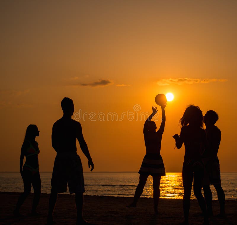 Siluetea a una gente joven en una playa fotografía de archivo Siluetea a una gente joven en una playa fotografía de archivo