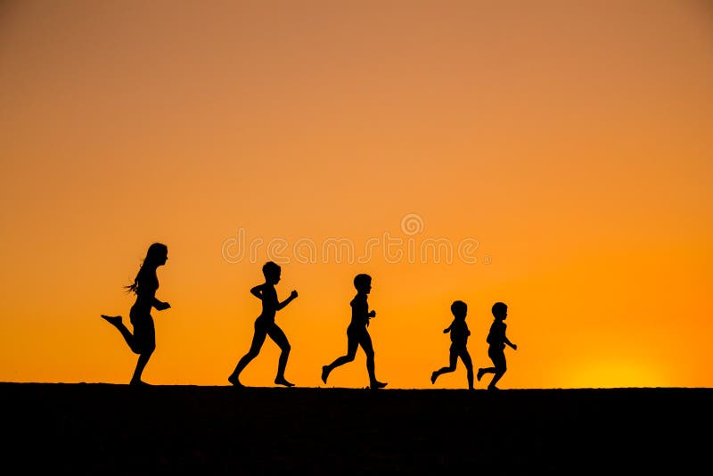 Siluetta dei bambini correnti contro il tramonto fotografia stock libera da diritti Siluetta dei bambini correnti contro il tramonto fotografia stock libera da diritti