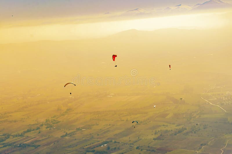 Siluetta del paraglide che sorvola le alte montagne fotografia stock Siluetta del paraglide che sorvola le alte montagne fotografia stock