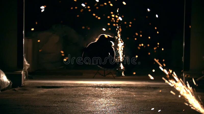 Siluetta dell'uomo che esegue gli elementi marziali attraverso le scintille dalla smerigliatrice alla notte