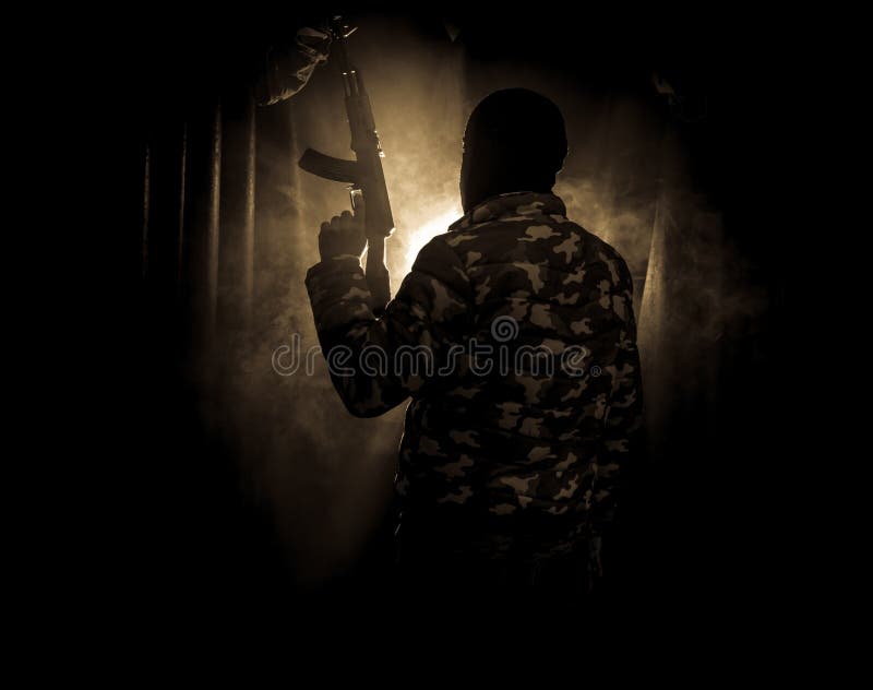 Siluetta dell'uomo con il fucile di assalto pronto ad attaccare su fondo nebbioso tonificato scuro o sul bandito pericoloso in pa fotografia stock Siluetta dell'uomo con il fucile di assalto pronto ad attaccare su fondo nebbioso tonificato scuro o sul bandito pericoloso in pa fotografia stock