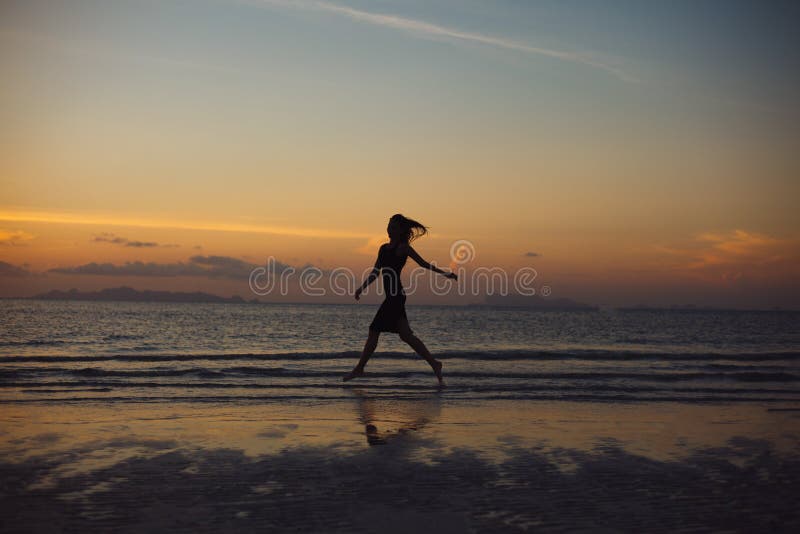 siluetta della donna che corre sulla spiaggia dell'oceano fotografia stock libera da diritti siluetta della donna che corre sulla spiaggia dell'oceano fotografia stock libera da diritti