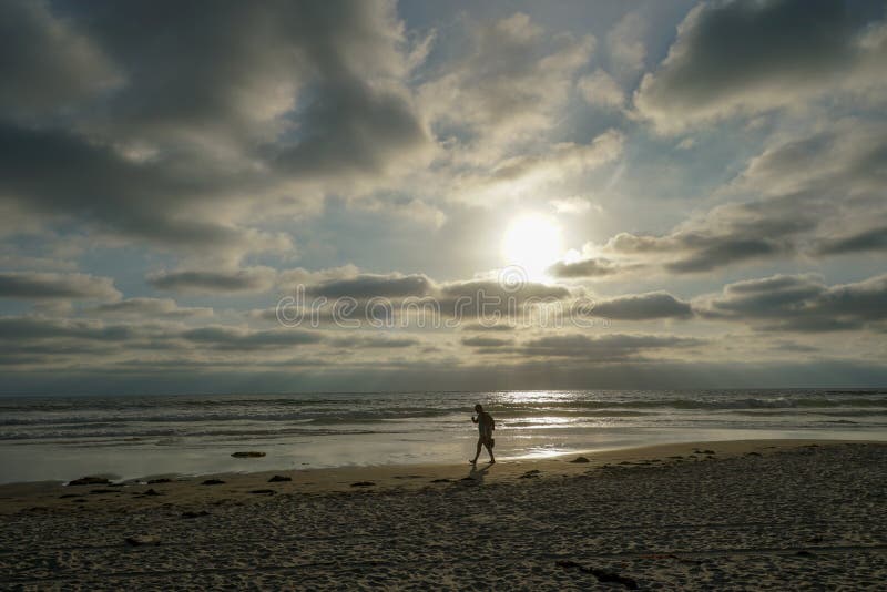 Silhouette of people enjoying and walking during peaceful moment of sunset at the beach. Beautiful sky on twilight time and reflection on the sea. La Jolla, San Diego, California, USA. Silhouette of people enjoying and walking during peaceful moment of sunset at the beach. Beautiful sky on twilight time and reflection on the sea. La Jolla, San Diego, California, USA