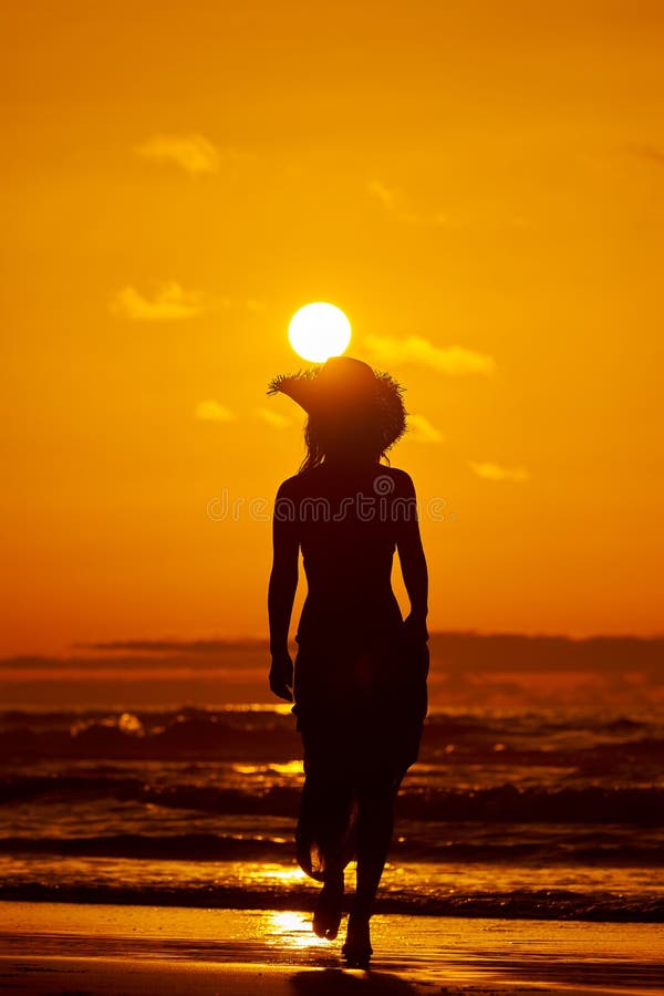 Siluetta della giovane donna sulla spiaggia nel tramonto di estate immagini stock libere da diritti Siluetta della giovane donna sulla spiaggia nel tramonto di estate immagini stock libere da diritti