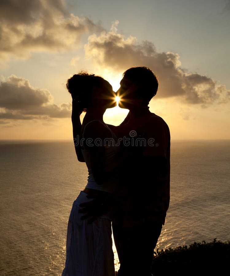 Siluetta di giovane coppia al tramonto fotografia stock Siluetta di giovane coppia al tramonto fotografia stock