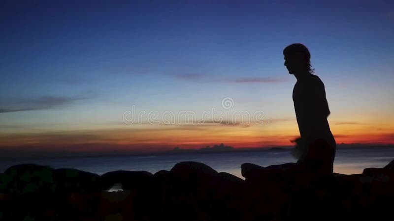 Siluetta di giovane uomo atletico che esegue addestramento al tramonto della spiaggia Movimento lento 1920x1080