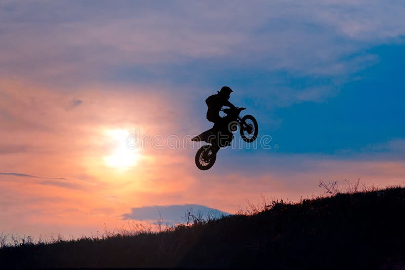 Siluetta di un cavaliere della motocicletta che arresta sul tramonto