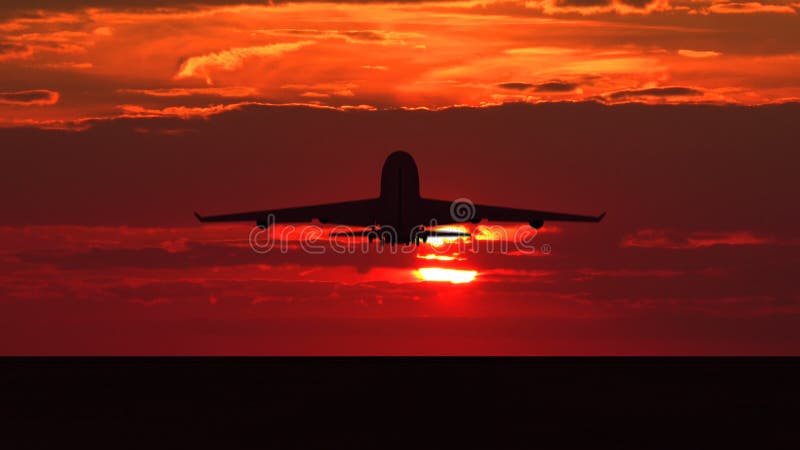 Siluetta di un grande aereo passeggeri che decolla contro il tramonto arancione