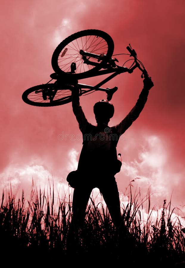 Siluetta di un motociclista che tiene la sua bicicletta fotografie stock libere da diritti Siluetta di un motociclista che tiene la sua bicicletta fotografie stock libere da diritti