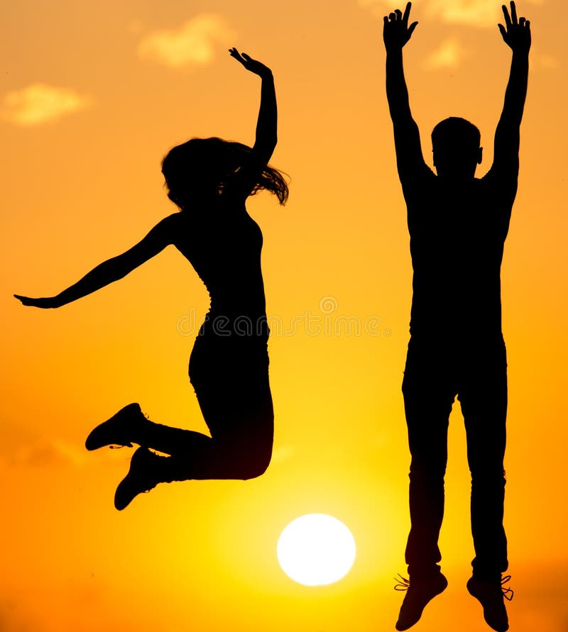 Siluetta di un tipo e di una ragazza al tramonto fotografia stock Siluetta di un tipo e di una ragazza al tramonto fotografia stock