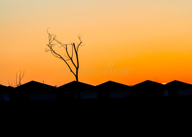 Siluetta urbana delle case della città al cielo arancio di tramonto fotografie stock Siluetta urbana delle case della città al cielo arancio di tramonto fotografie stock