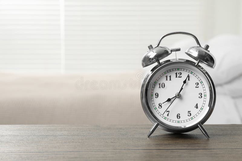 Silver Alarm Clock on Wooden Table in Bedroom, Space for Text Stock